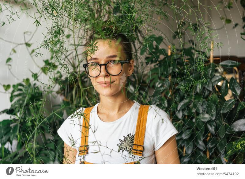 Porträt einer jungen Frau umgeben von Pflanzen Job Berufe Berufstätigkeit Beschäftigung Jobs Brillen Arbeit leidenschaftlich Leidenschaftlichkeit zufrieden