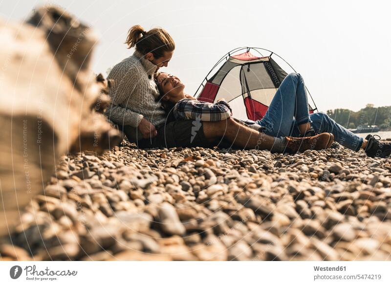 Glückliches junges Paar entspannt sich in einem Zelt am Flussufer glücklich glücklich sein glücklichsein Zelte Pärchen Paare Partnerschaft entspanntheit relaxt