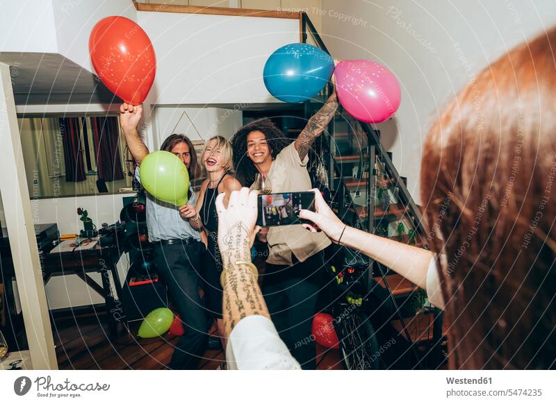 Frau fotografiert Freunde, die während einer Party zu Hause tanzen Farbaufnahme Farbe Farbfoto Farbphoto Innenaufnahme Innenaufnahmen innen drinnen