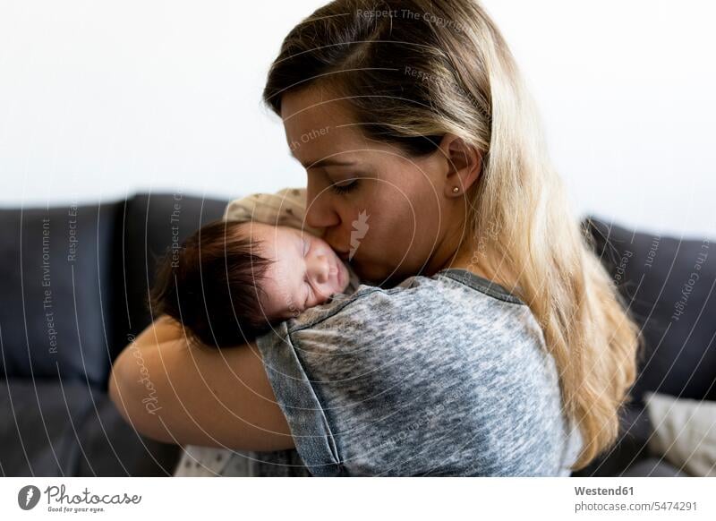 Mutter hält und küsst ihr neugeborenes Baby multikulturell glücklich Glück glücklich sein glücklichsein Augen geschlossen geschlossene Augen Gemeinsam Zusammen
