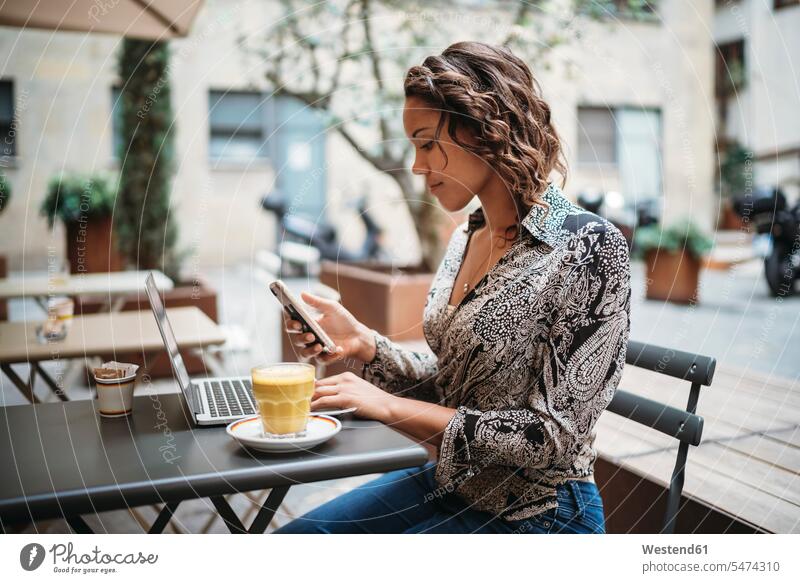 Junge Frau mit Laptop und Smartphone in einem Straßencafé Job Berufe Berufstätigkeit Beschäftigung Jobs geschäftlich Geschäftsleben Geschäftswelt