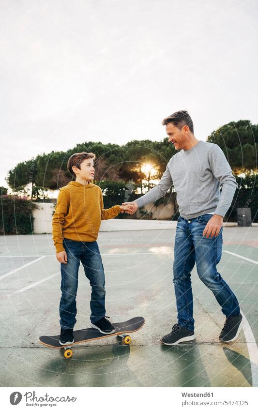 Vater assistiert Sohn beim Skateboardfahren Rollbretter Skateboards Papas Väter Vati Vatis Papis Söhne helfen mithelfen Hilfsbereitschaft beistehen Mithilfe