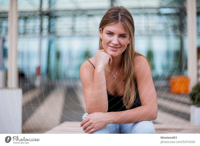 Porträt einer lächelnden jungen Frau, die im Freien sitzt sitzen sitzend Portrait Porträts Portraits weiblich Frauen Erwachsener erwachsen Mensch Menschen Leute