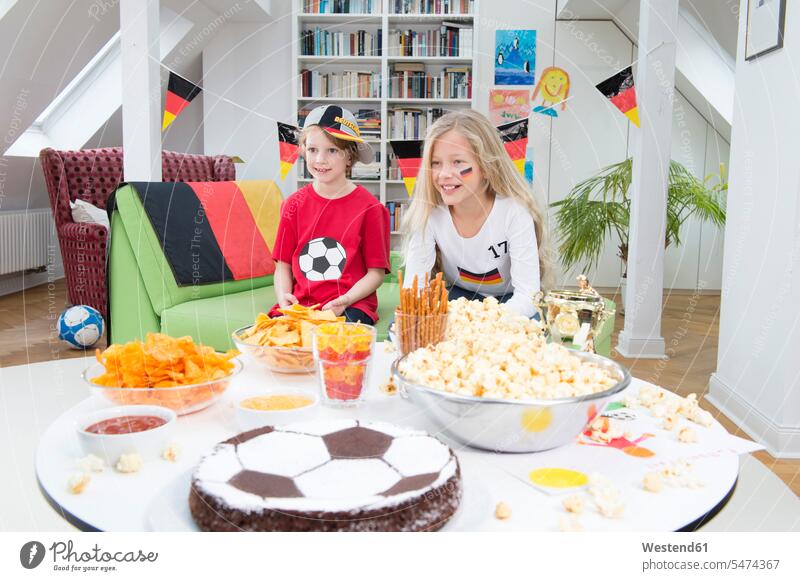 Geschwister sehen Fußball-Weltmeisterschaft mit Süßigkeiten und Snacks Zuhause zu Hause daheim Freunde Fussball Fahne Fahnen Knabberei Knabbereien Gemeinsam