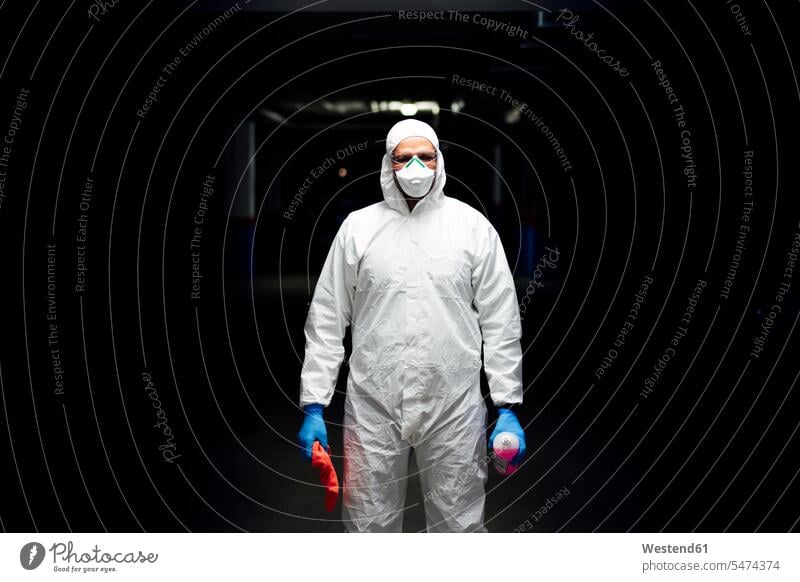 Reinigungspersonal im Anzug mit Desinfektionsmittel und Reinigungstuch Masken reinigen nachts weiss weiße weißer weißes stehend steht hygienisch geschützt