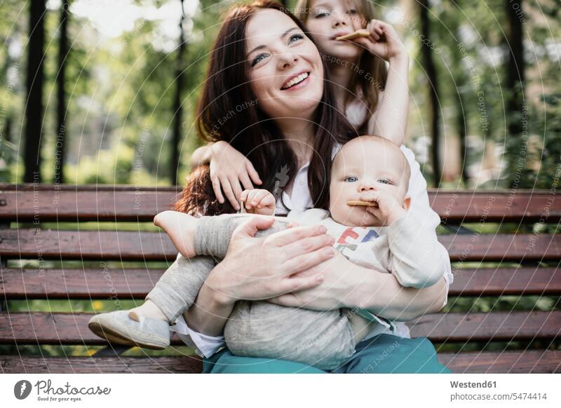 Lächelnde Mutter mit ihren beiden Kindern beim Keksessen im Park Leute Menschen People Person Personen Europäisch Kaukasier kaukasisch Gruppe von Menschen