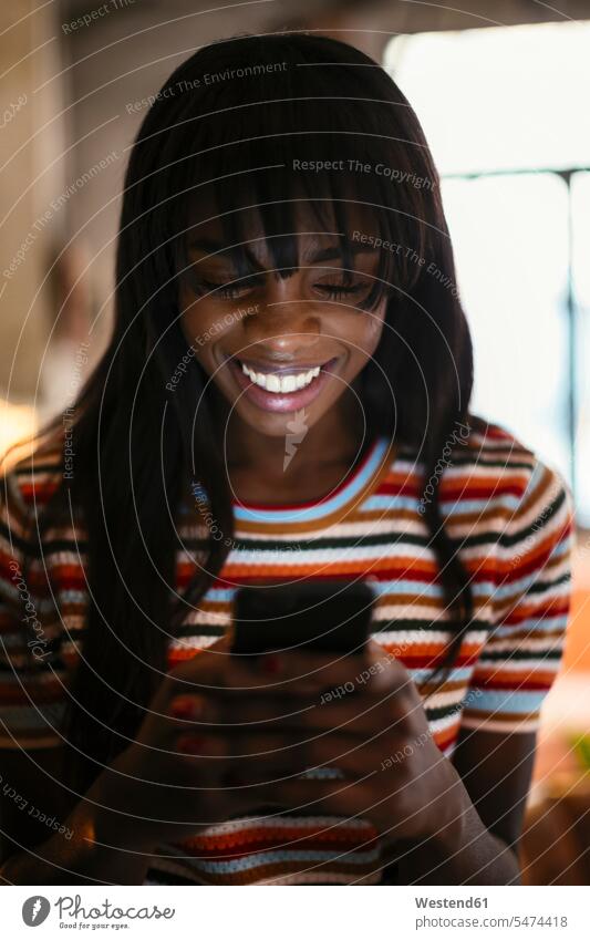 Porträt einer glücklichen jungen Frau, die auf ein Handy schaut Portrait Porträts Portraits schauen schauend anschauen betrachten Glück glücklich sein