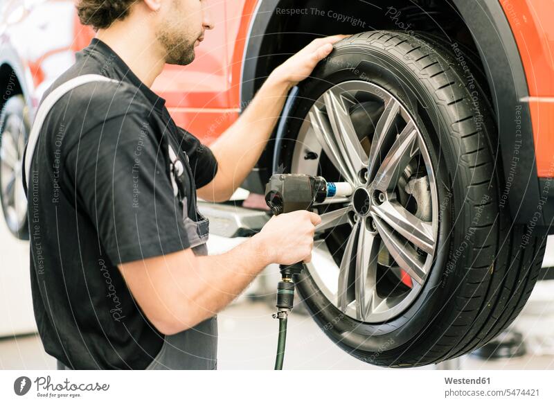 Automechaniker in einer Werkstatt beim Reifenwechsel Job Berufe Berufstätigkeit Beschäftigung Jobs Gewerbe industriell Industrien Monteur KFZ Verkehrsmittel
