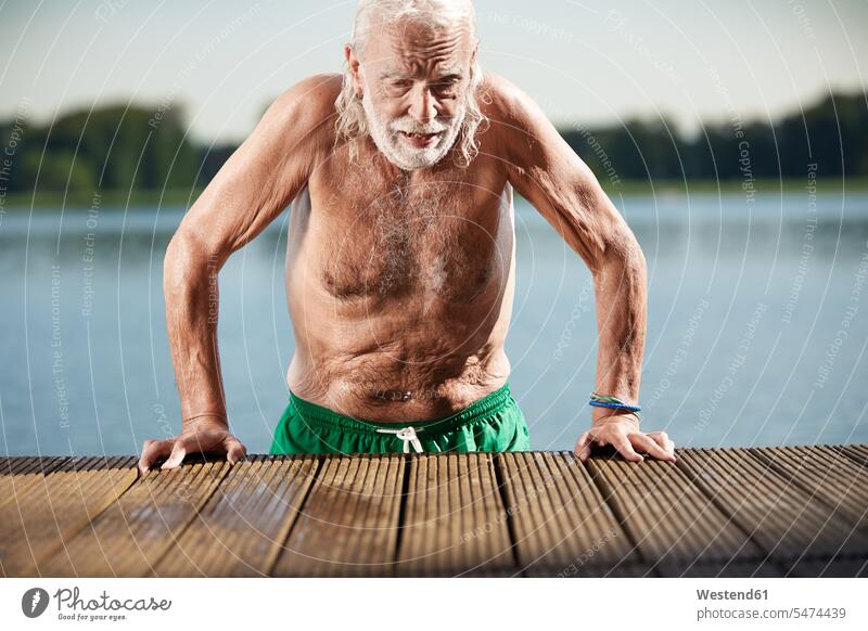Porträt eines älteren Mannes, der sich an einen Steg am See lehnt Seen Portrait Porträts Portraits aufstützen aufgestuetzt aufgestützt Senior ältere Männer