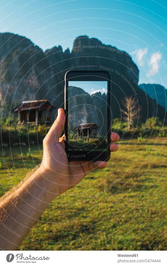 Laos, Handheld-Smartphone, Display mit Holzhütte und Bergen Betrachtung Nachsinnen betrachten Kontemplation Hütte Hütten iPhone Smartphones fotografieren