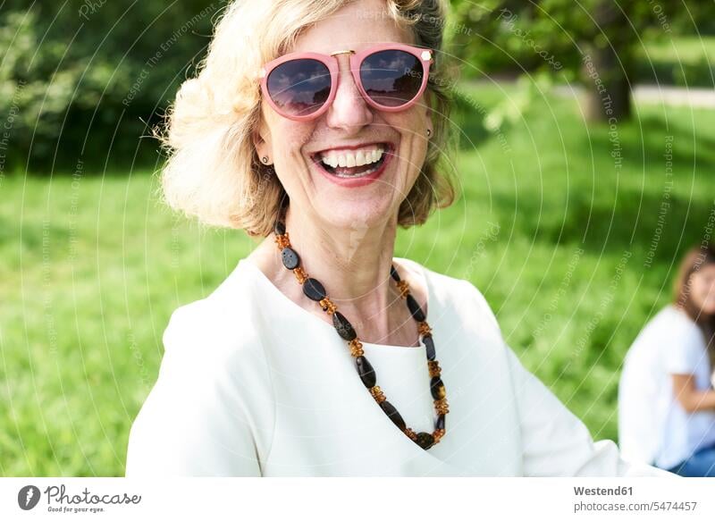 Porträt einer glücklichen älteren Frau mit Sonnenbrille im Park Sonnenbrillen Brille weiblich Frauen Parkanlagen Parks Portrait Porträts Portraits Glück