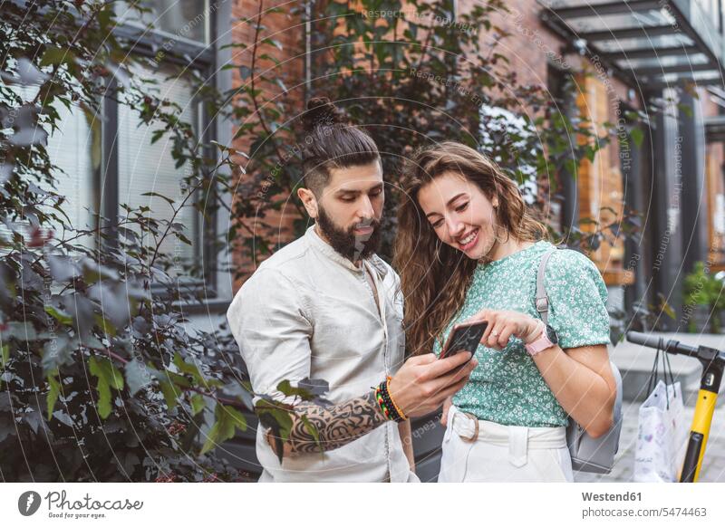 Ehepaar betrachtet Smartphone, während es auf einem Fußweg in der Stadt steht Farbaufnahme Farbe Farbfoto Farbphoto Moskau Zentralrussland Russland