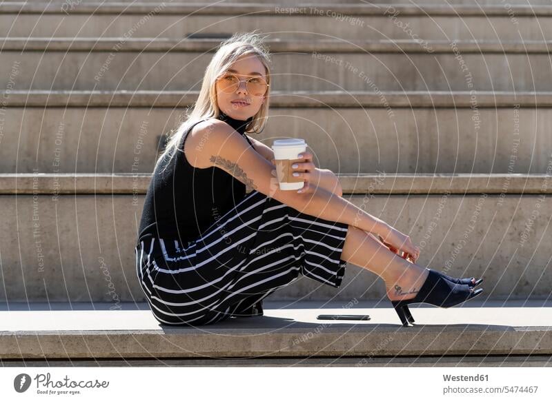 Bortrait von blonden jungen Frau mit Kaffee zu gehen sitzen auf Treppen im Freien Spanien Coffee to go zum mitnehmen schön Smartphone iPhone Smartphones