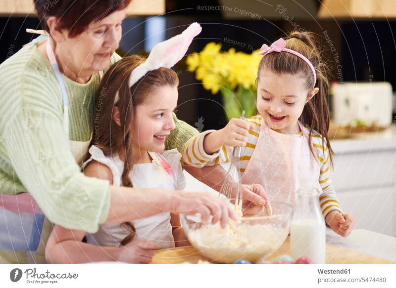 Großmutter und Enkelinnen backen gemeinsam Osterplätzchen in der Küche Keks Kekse Plaetzchen Plätzchen Grossmutter Oma Grossmama Großmütter Omi Enkeltochter