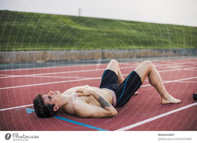 Sportler liegend auf einer Tartanbahn nach Beendigung eines Rennens Südeuropäer Südeuropäisch liegt trainieren Ehrgeiz ehrgeizig fit ausruhen Rast Erholung