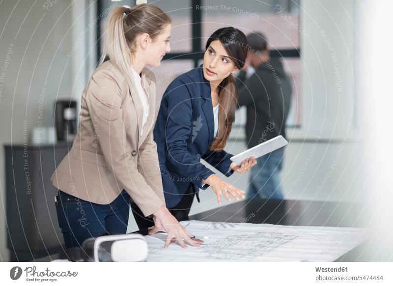 Zwei junge Frauen mit Tablett und VR-Brille arbeiten im Büro an der Blaupause Office Büros weiblich Brillen Arbeit Bauplan Architekturplan Konstruktionsplan
