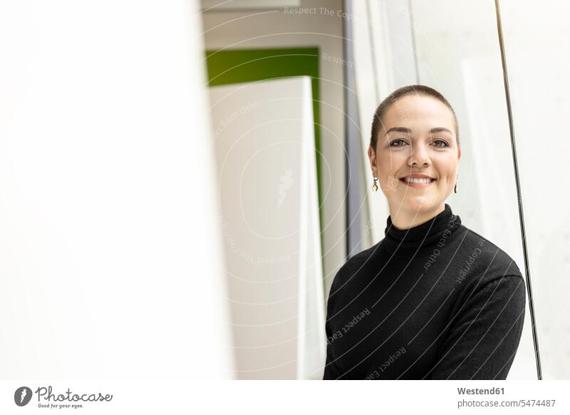 Porträt einer lächelnden jungen Frau am Fenster im Büro Europäer eine Person junge Frau 20-25 Jahre Business Deutschland Innenaufnahme modern Beruf