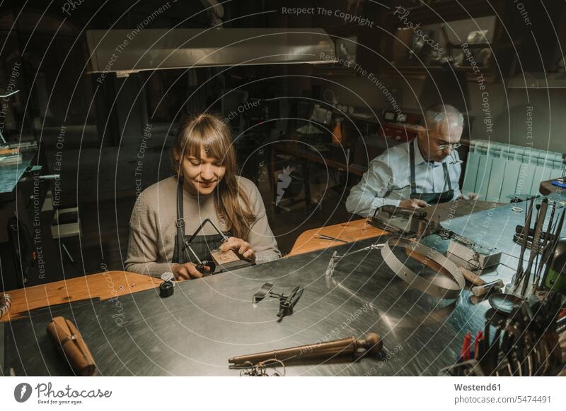 Kunsthandwerker und sein Mitarbeiter bei der Herstellung von Schmuck in seiner Werkstatt Europäer Kaukasier Europäisch kaukasisch Arbeitstisch Arbeitstische