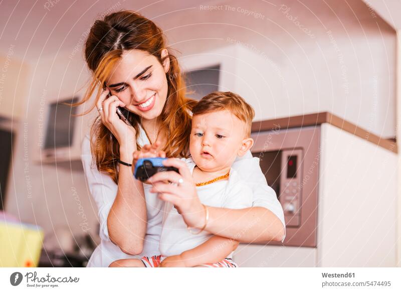 Glückliche Mutter mit ihrem Sohn telefoniert zu Hause Leute Menschen People Person Personen Europäisch Kaukasier kaukasisch 2 2 Menschen 2 Personen zwei