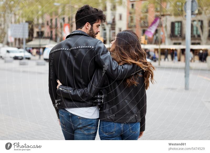 Spanien, Barcelona, junges Paar bei Umarmung und Spaziergang in der Stadt umarmen Umarmungen Arm umlegen staedtisch städtisch Pärchen Paare Partnerschaft gehen