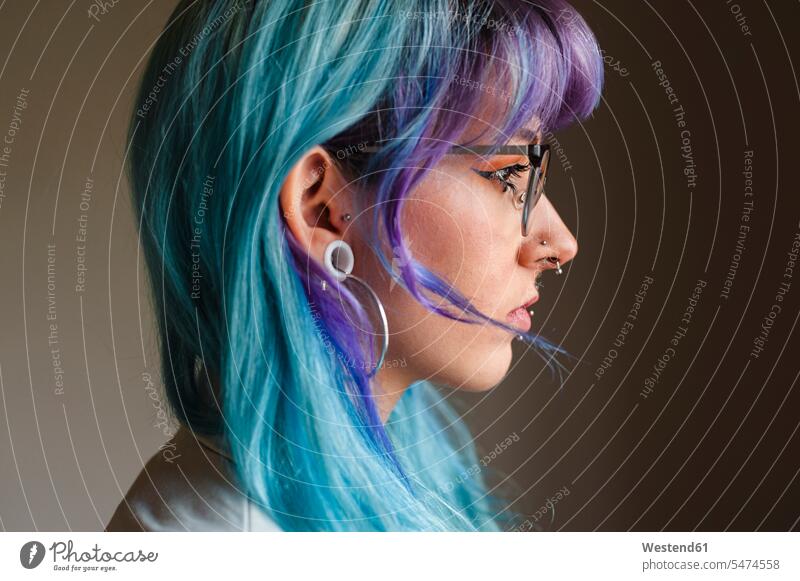 Nahaufnahme einer nachdenklichen jungen Frau mit gefärbten Haaren und Piercings an der Wand in einem alten Büro Farbaufnahme Farbe Farbfoto Farbphoto