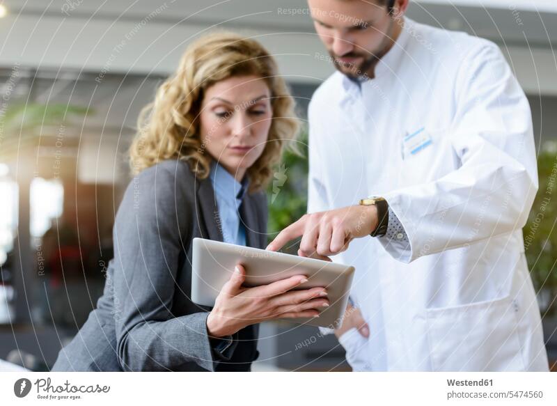 Geschäftsfrau mit Tablette und Arzt im Gespräch im Krankenhaus Job Berufe Berufstätigkeit Beschäftigung Jobs geschäftlich Geschäftsleben Geschäftswelt