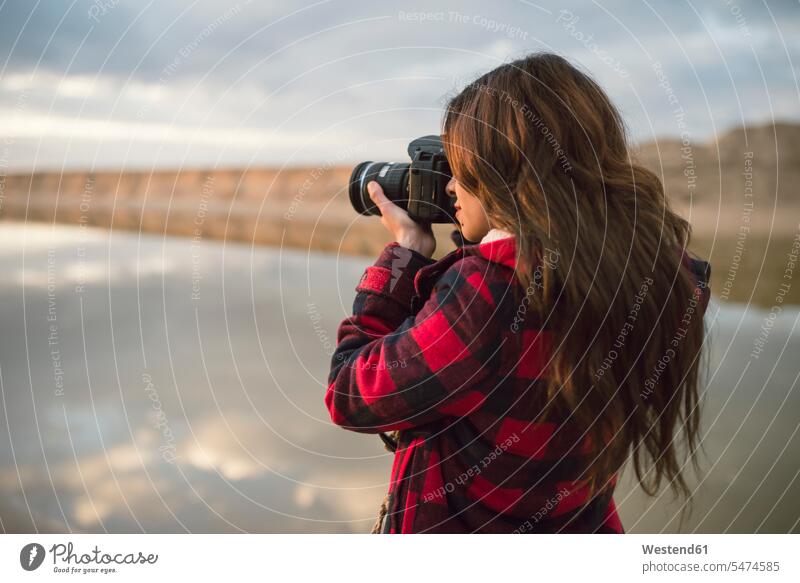 Junge Frau nimmt Bild mit Kamera am Strand Beach Straende Strände Beaches weiblich Frauen fotografieren Kameras Fotoapparat Fotokamera Erwachsener erwachsen