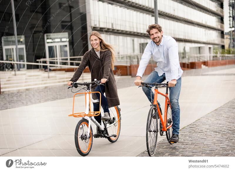 Lächelndes Paar beim Fahrradfahren in der Stadt Bikes Fahrräder Räder Rad fahrradfahren radeln Pärchen Paare Partnerschaft staedtisch städtisch lächeln Raeder