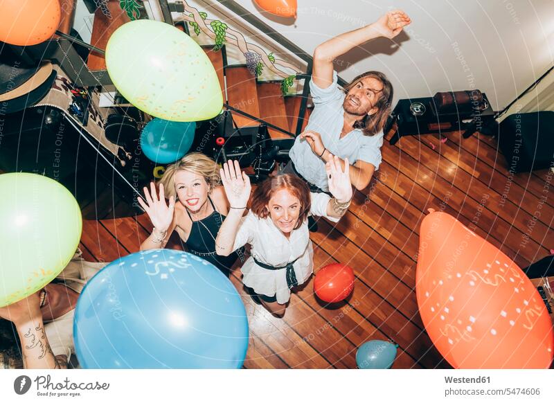 Männliche und weibliche Freunde tanzen mit bunten Luftballons während einer Party zu Hause Farbaufnahme Farbe Farbfoto Farbphoto Innenaufnahme Innenaufnahmen