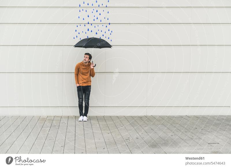 Digitales Komposit eines jungen Mannes, der einen Regenschirm an eine Wand mit Regentropfen hält Leute Menschen People Person Personen Europäisch Kaukasier