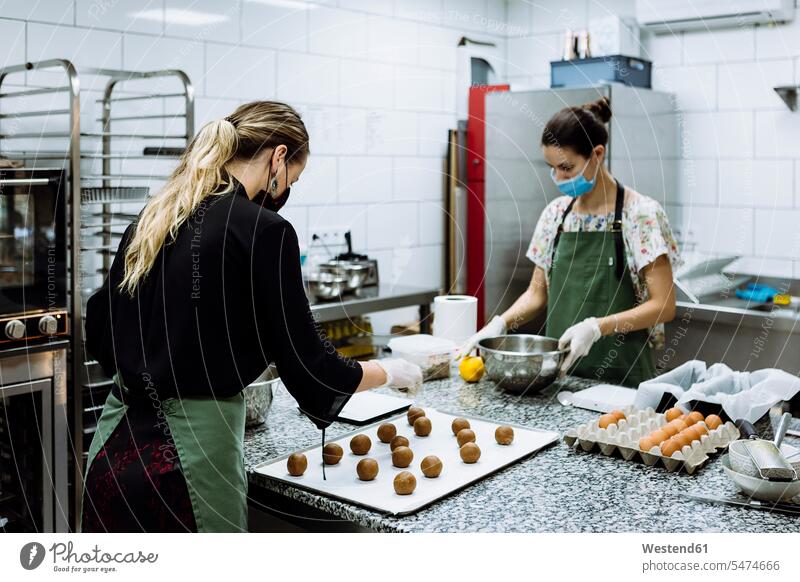 Bäckerinnen, die während COVID-19 in der Küche in einer Bäckerei Kekse backen Farbaufnahme Farbe Farbfoto Farbphoto Spanien Innenaufnahme Innenaufnahmen drinnen