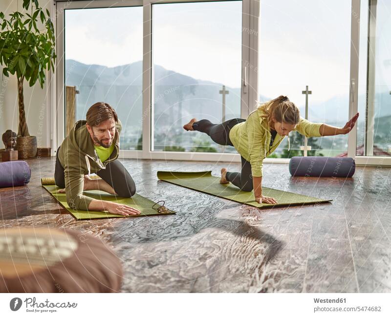 Yoga praktizierendes Paar in einem Raum mit Panoramafenster Yoga-Übungen Yogauebungen Yogaübungen Jogauebung Jogauebungen Fenster Pärchen Paare Partnerschaft