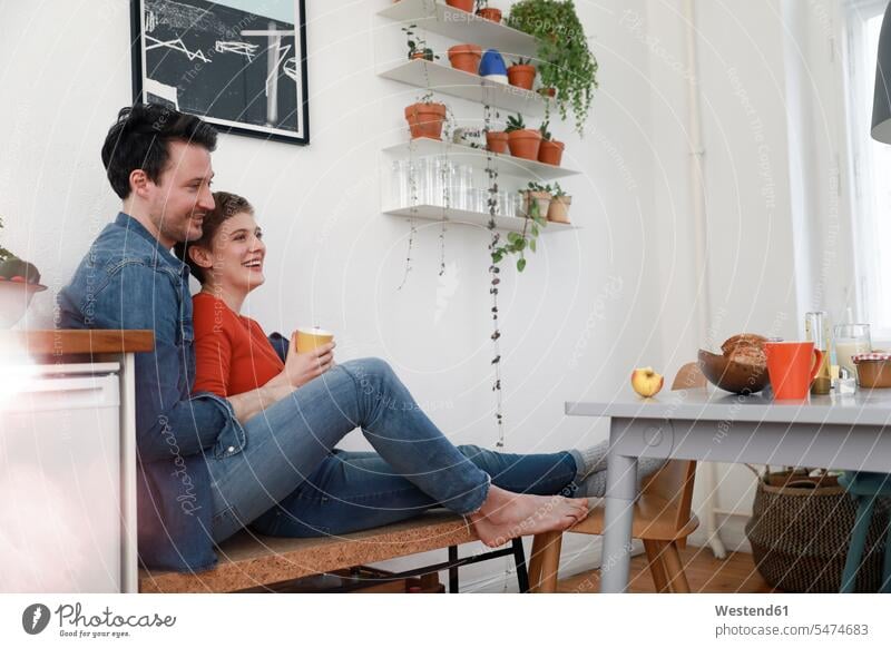 Glückliches Paar, das in der Küche sitzt und sich aneinander lehnt Pärchen Paare Partnerschaft anlehnen angelehnt lehnend glücklich glücklich sein glücklichsein