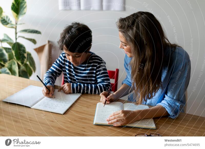 Junge Frau sitzt mit Studentin zusammen und macht zu Hause Hausaufgaben auf dem Tisch Farbaufnahme Farbe Farbfoto Farbphoto Spanien Freizeitkleidung