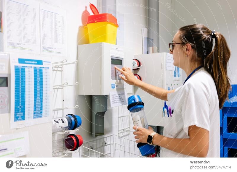 Ärztin, die im Krankenhaus stehend ein Rohrpostsystem verwendet Farbaufnahme Farbe Farbfoto Farbphoto Spanien Innenaufnahme Innenaufnahmen innen drinnen Medizin