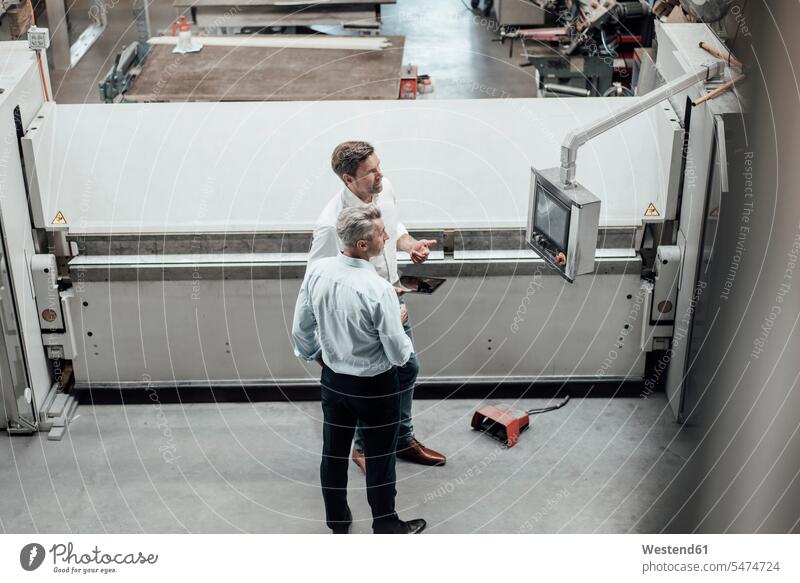 Reife männliche Ingenieure diskutieren über Fertigungsanlagen in der Fabrik Farbaufnahme Farbe Farbfoto Farbphoto Deutschland Innenaufnahme Innenaufnahmen innen