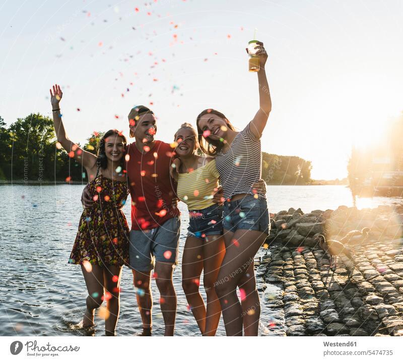 Konfetti um eine Gruppe glücklicher Freunde, die sich bei Sonnenuntergang in einem Fluss vergnügen Spaß Spass Späße spassig Spässe spaßig Sonnenuntergänge Glück