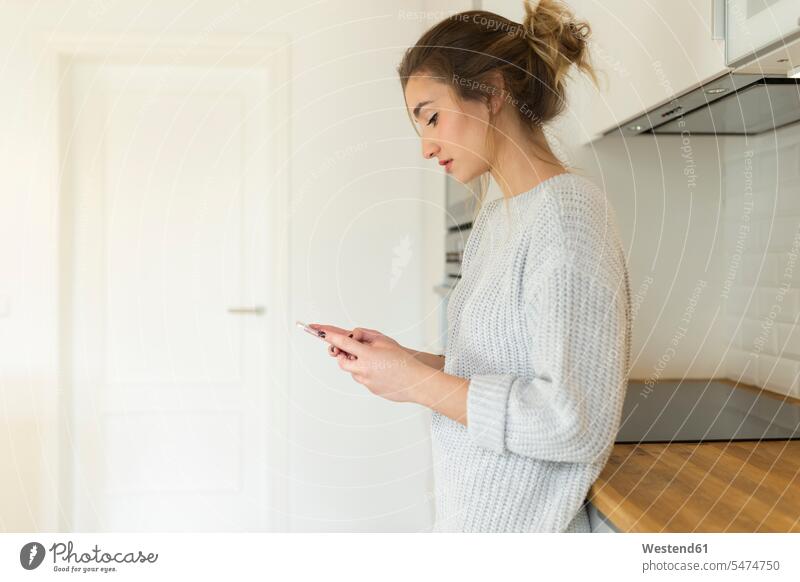 Junge Frau benutzt Smartphone zu Hause Telekommunikation telefonieren Handies Handys Mobiltelefon Mobiltelefone Lektüre sitzend sitzt Anruf anrufen