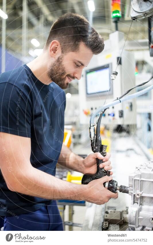 Mann arbeitet in einer modernen Fabrik Job Berufe Berufstätigkeit Beschäftigung Jobs Arbeiter T-Shirts Geräte Werkzeuge zufrieden stehend steht Arbeitsstätte