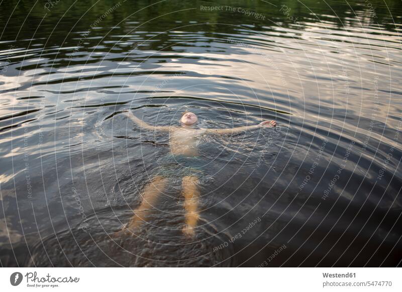Junge schwimmend in einem See am Abend abends sommerlich Sommerzeit erfrischen erfrischend Muße Urlaub Wasser Seen Wasseroberflaeche Wasseroberflaechen