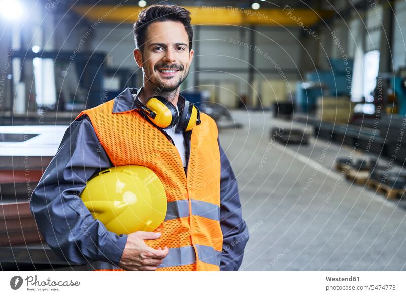 Porträt eines lächelnden Mannes mit Arbeitsschutzkleidung in der Fabrik Portrait Porträts Portraits Schutzkleidung Männer männlich Fabrikgebäude Fabrikgebaeude