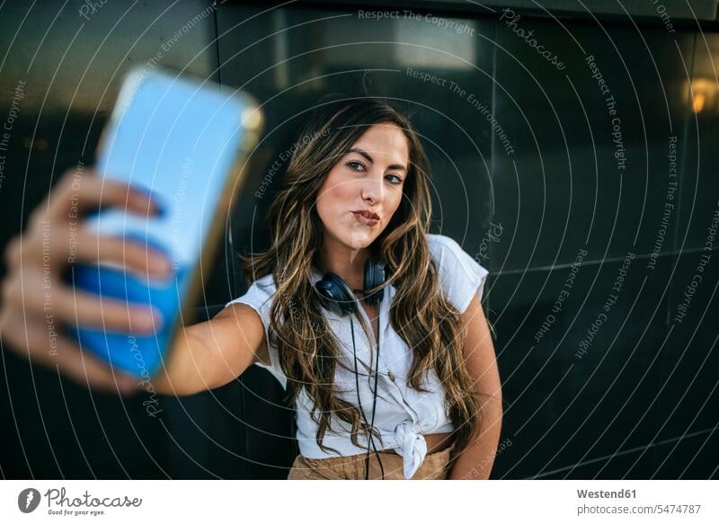 Junge Frau, die ein Selfie mit ihrem Smartphone macht, schmollender Mund Leute Menschen People Person Personen Europäisch Kaukasier kaukasisch 1 Ein ein Mensch