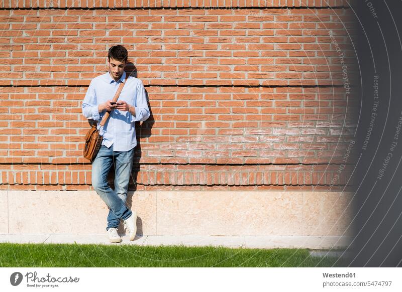 Junger Mann benutzt Smartphone in der Stadt Hemden Telekommunikation telefonieren Handies Handys Mobiltelefon Mobiltelefone Arbeit Lektüre Anruf anrufen