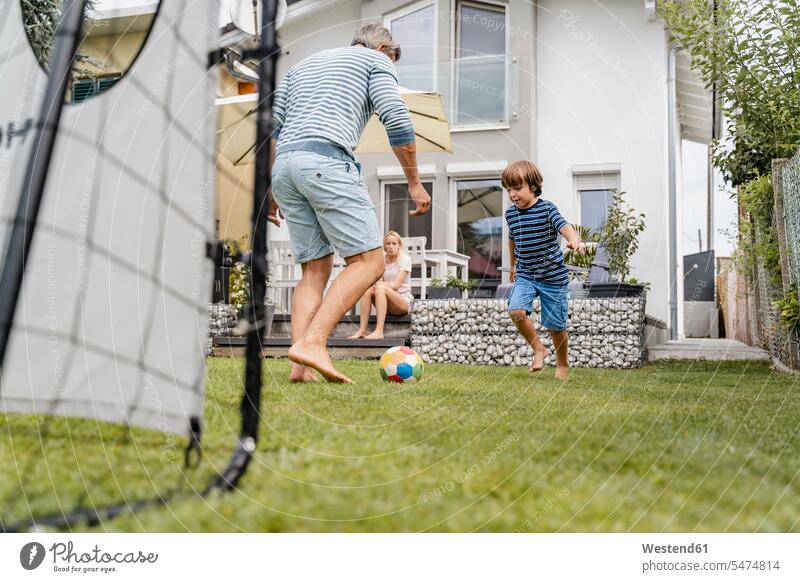Vater und Sohn spielen im Garten Fussball Bälle Fußbälle rennen sommerlich Sommerzeit begeistert Enthusiasmus enthusiastisch Überschwang Überschwenglichkeit