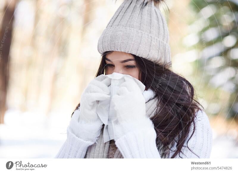 Junge Frau schnäuzt sich im Winter die Nase weiblich Frauen Nase putzen schnäuzen winterlich Winterzeit Erwachsener erwachsen Mensch Menschen Leute People
