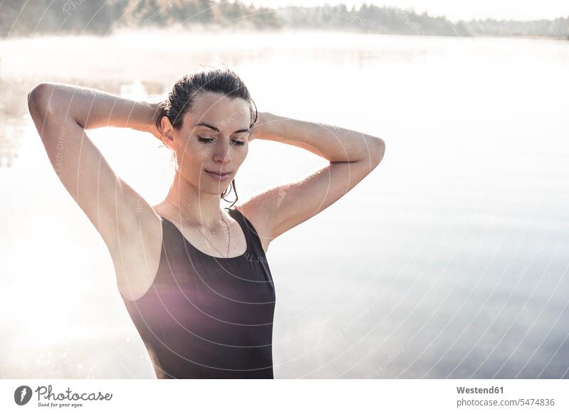 Frau im schwarzen Badeanzug an einem See im Morgennebel Badebekleidung Badeanzuege Badeanzüge früh Frühe entspannen relaxen entspanntheit relaxt geniessen