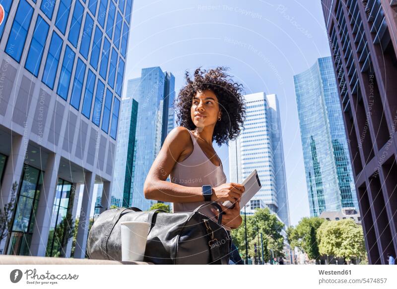 Deutschland, Frankfurt, Porträt einer jungen Frau mit Reisetasche, Tablette und Kaffee zum Mitnehmen in der Stadt Tablet Computer Tablet-PC Tablet PC iPad