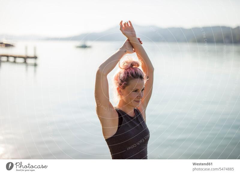 Frau in Sportkleidung beim Stretching an einem See Seen Yoga weiblich Frauen strecken dehnen Sportbekleidung Sportdress Kleidung Gewässer Wasser Erwachsener