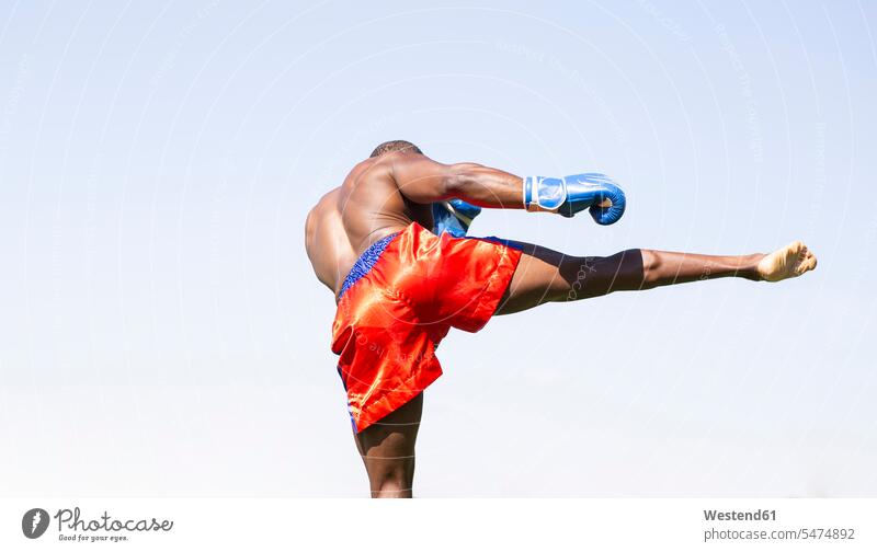 Aktive männliche Sportler tun Boxen Übung gegen klaren Himmel am sonnigen Tag Farbaufnahme Farbe Farbfoto Farbphoto Außenaufnahme außen draußen im Freien