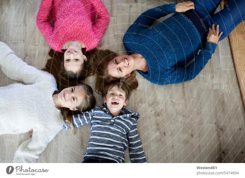 Glückliche Familie auf dem Boden liegend, lachend Geborgenheit geborgen behütet Sicherheit behüten Freizeitkleidung casual Freizeitbekleidung Vergnügen genießen